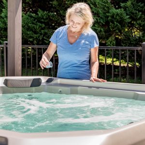 A woman adding an Ahh!some hot tub cleaner product to her hot tub