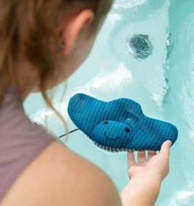 A woman is holding a ScumRay over hot tub water.