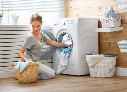 A woman pulling fresh laundry out of her washing machine.
