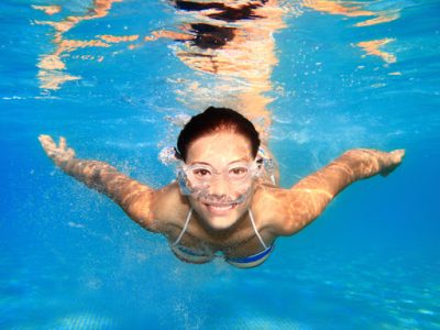woman swimming in clear pool water thanks to pool pipe cleaning